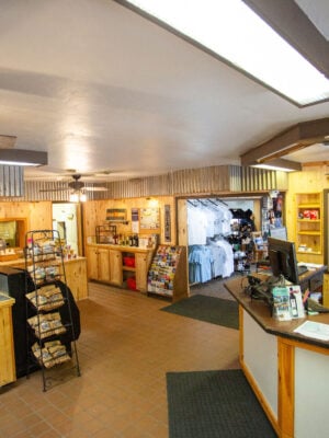 Gift shop interior with wood-paneled walls, merchandise displays, souvenirs, a checkout counter, and overhead lighting.